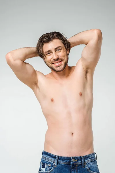 Portrait of smiling shirtless man in jeans looking at camera on grey backdrop — Stock Photo