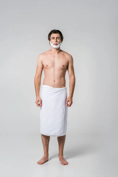 Homem sem camisa em toalha com espuma de barbear no rosto isolado no cinza — Fotografia de Stock