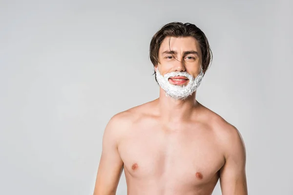 Portrait de jeune homme avec mousse à raser sur le visage regardant caméra isolée sur gris — Photo de stock