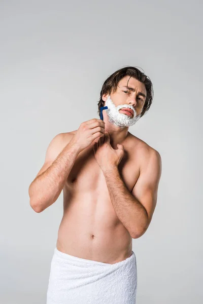 Retrato de hombre joven en toalla blanca con espuma de afeitar en la barba de afeitar de la cara aislado en gris - foto de stock