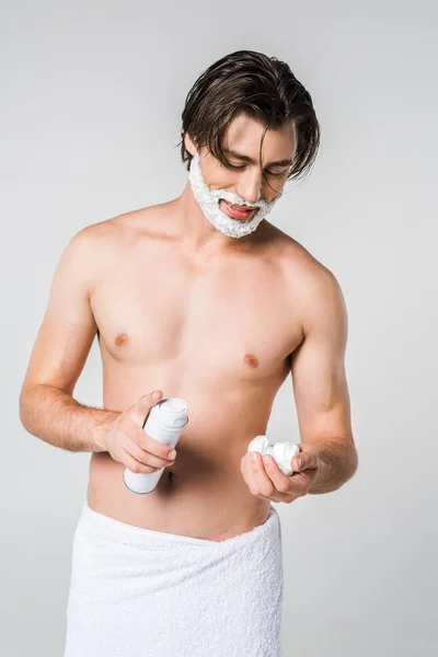 Портрет молодого чоловіка в білому рушнику з піною для гоління ізольовано на сірому — стокове фото