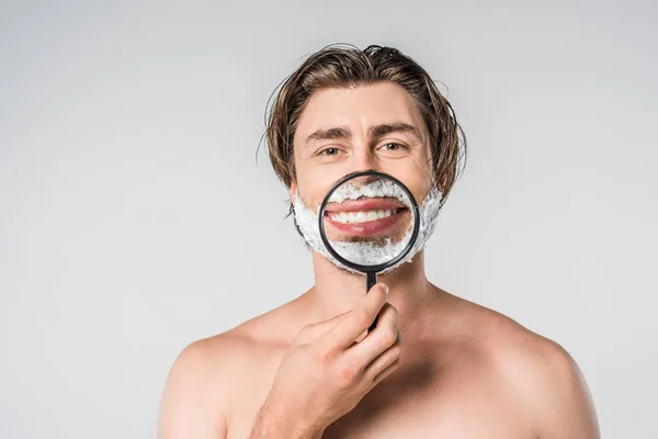 Portrait d'homme souriant avec mousse à raser sur le visage et loupe isolée sur gris — Photo de stock