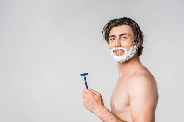 Side view of young man with shaving foam holding razor isolated on grey — Stock Photo