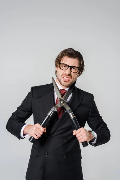 Портрет разъяренного бизнесмена в черном костюме с клиппером в руках, изолированных на сером — стоковое фото