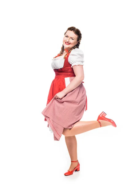 Serveuse souriante oktoberfest en robe bavaroise traditionnelle debout sur une jambe isolée sur fond blanc — Photo de stock