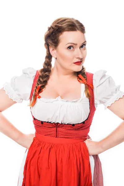 Красива офіціантка в традиційній баварській сукні, що стоїть з руками на талії ізольована на білому тлі — стокове фото