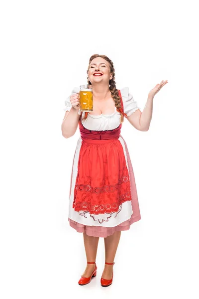 Excited oktoberfest waitress in traditional bavarian dress smelling light beer isolated on white background — Stock Photo