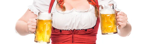Imagen recortada de camarera oktoberfest en vestido bavariano tradicional sosteniendo tazas de cerveza ligera aislada sobre fondo blanco - foto de stock