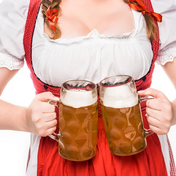 Vista parcial da garçonete oktoberfest em vestido tradicional alemão segurando canecas de cerveja leve isolada no fundo branco — Fotografia de Stock