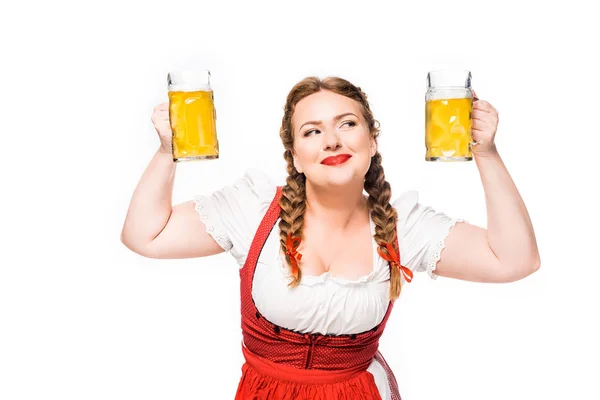 Smiling oktoberfest waitress in traditional bavarian dress showing mugs of light beer isolated on white background — Stock Photo