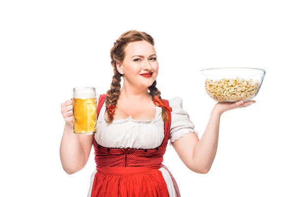 Щаслива офіціантка в традиційній баварській сукні, що тримає миску попкорну та кухоль легкого пива ізольовано на білому тлі — стокове фото
