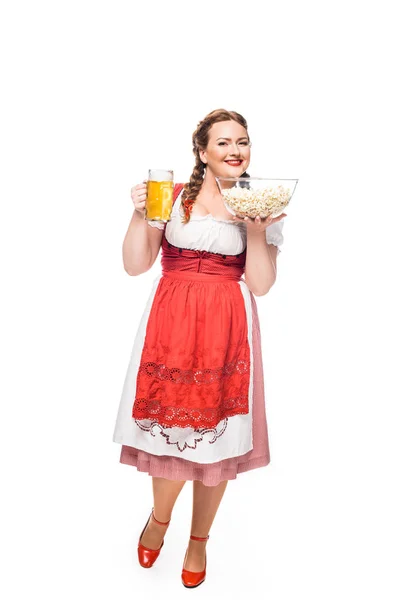 Oktoberfest camarera en vestido bavariano tradicional sosteniendo taza de cerveza ligera y palomitas de maíz aisladas sobre fondo blanco - foto de stock