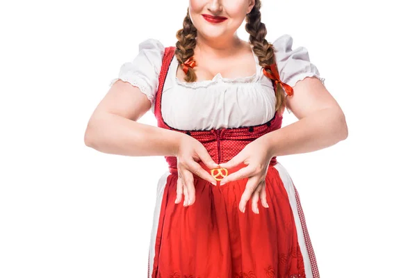Cropped image of oktoberfest waitress in traditional bavarian dress making heart symbol by hands and little pretzel isolated on white background — Stock Photo