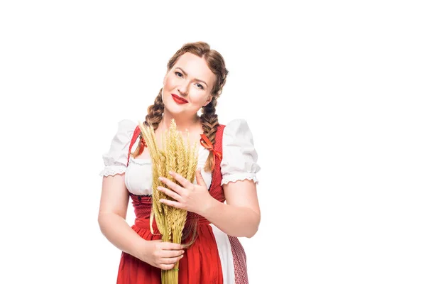 Smiling oktoberfest waitress in traditional bavarian dress holding wheat ears isolated on white background — Stock Photo