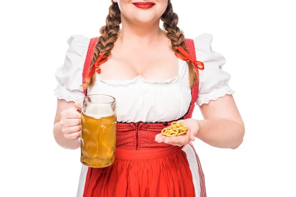 Imagem cortada de garçonete oktoberfest em vestido tradicional bávaro mostrando pequenos pretzels e caneca de cerveja leve isolada no fundo branco — Fotografia de Stock