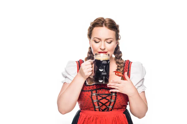 Oktoberfest waitress in traditional bavarian dress drinking dark beer isolated on white background — Stock Photo