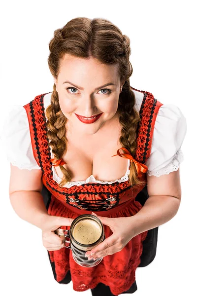 High angle view of smiling oktoberfest waitress in traditional bavarian dress holding mug of dark beer isolated on white background — Stock Photo