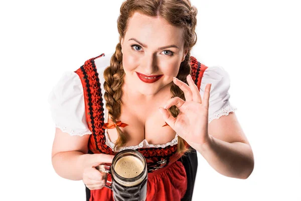 Vista ad alto angolo della cameriera oktoberfest in abito tradizionale bavarese che tiene tazza di birra scura e mostra segno ok isolato su sfondo bianco — Foto stock