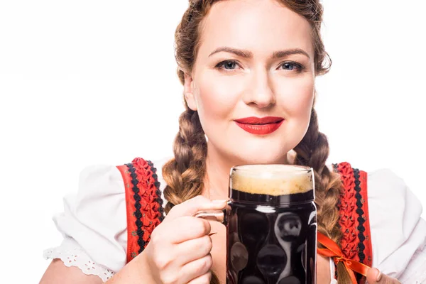 Smiing oktoberfest waitress in traditional bavarian dress holding mug of dark beer isolated on white background — Stock Photo