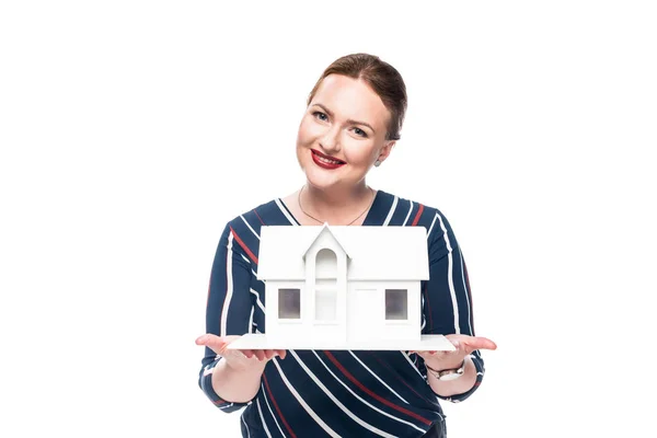 Smiling female estate agent presenting maquette of house isolated on white background — Stock Photo