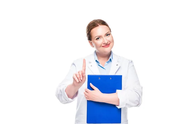 Sonriente médico femenino sosteniendo portapapeles y haciendo gesto de idea aislado sobre fondo blanco - foto de stock