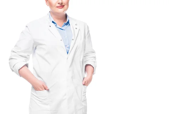 Image recadrée de femme médecin en manteau blanc avec les mains dans des poches isolées sur fond blanc — Photo de stock