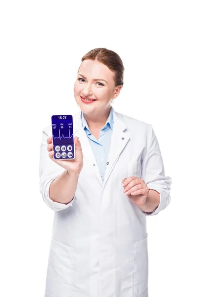 Sorridente médico do sexo feminino apresentando smartphone com monitor de frequência cardíaca na tela isolado em fundo branco — Fotografia de Stock