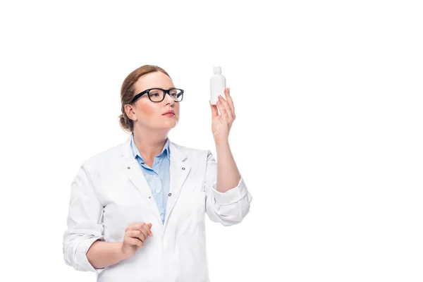 Female doctor in eyeglasses looking at pill bottle isolated on white background — Stock Photo