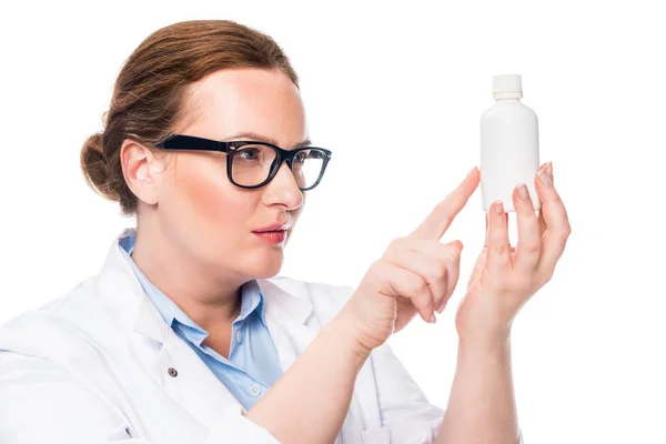 Médecin féminin confiant dans les lunettes pointant vers la bouteille de pilule isolé sur fond blanc — Photo de stock