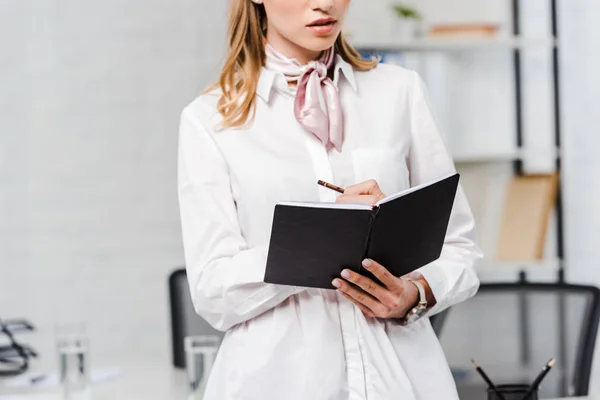 Plan recadré de jeune femme d'affaires prenant note au bureau moderne — Photo de stock