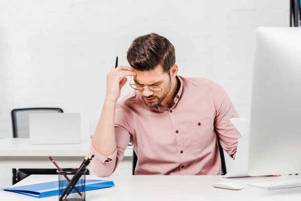 Thoughtful young businessman sitting at modern office — Stock Photo