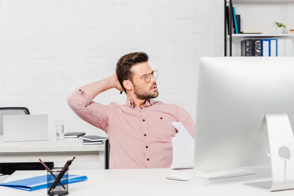 Overworked young businessman stretching at modern office — Stock Photo