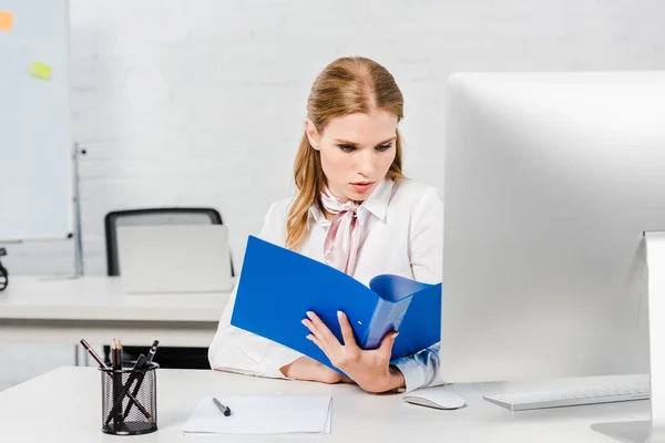 Concentrata giovane donna d'affari che legge documenti presso l'ufficio moderno — Foto stock