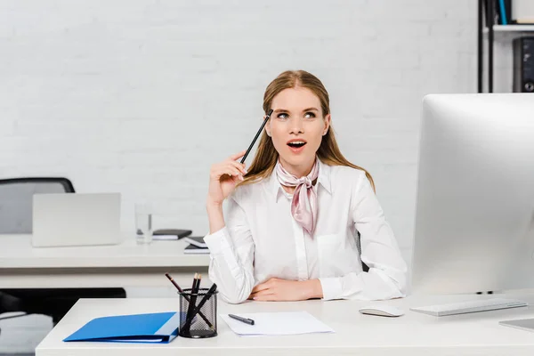 Thoughtful emotional young businesswoman looking up at modern office — Stock Photo