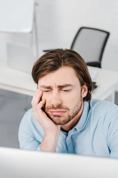 Close-up portrait of depressed young businessman sitting at modern office — Stock Photo