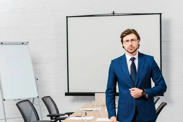 Apuesto joven empresario en la sala de conferencias con tablero de presentación en blanco - foto de stock