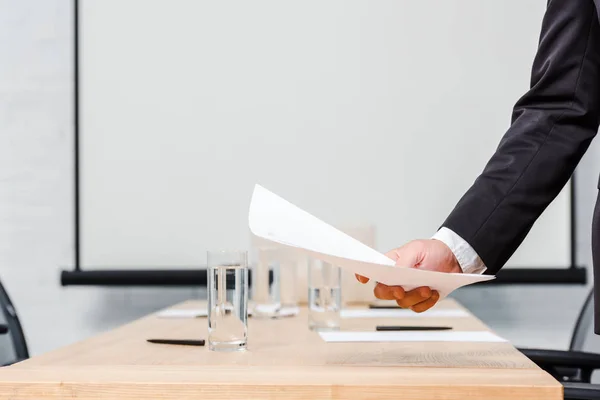 Colpo ritagliato di uomo d'affari che tiene la carta sopra il tavolo di conferenza all'ufficio — Foto stock