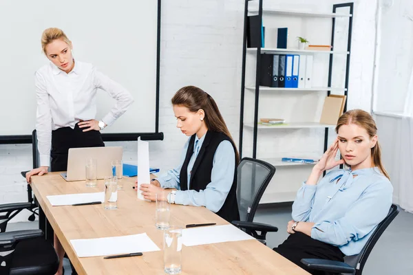 Angry lady boss talking to depressed female employees at modern office — Stock Photo