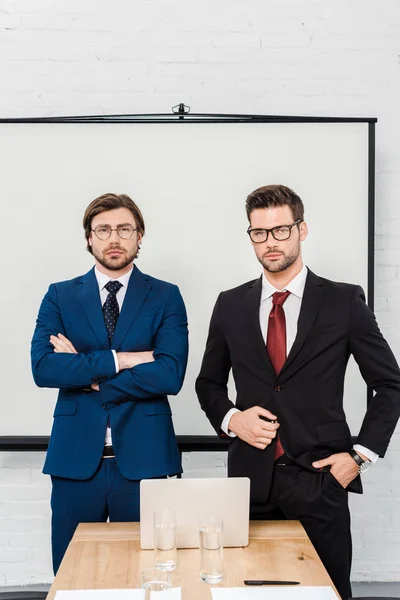 Beaux hommes d'affaires prospères regardant la caméra au bureau moderne — Photo de stock