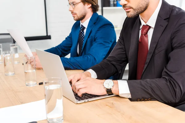 Colpo ritagliato di uomini d'affari che lavorano con documenti e computer portatile insieme a ufficio moderno — Foto stock