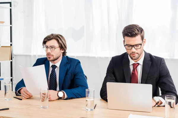 Empresários de sucesso trabalhando com documentos e laptop juntos no escritório moderno — Fotografia de Stock