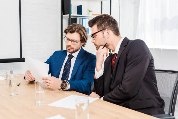 Gut aussehende erfolgreiche Geschäftsleute, die in modernen Büros gemeinsam mit Dokumenten arbeiten — Stockfoto