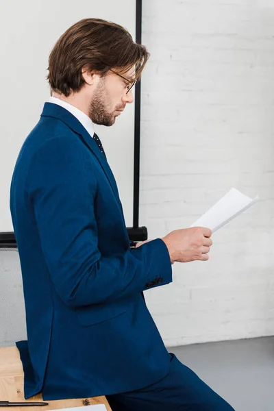 Concentrato giovane uomo d'affari la lettura di documenti presso l'ufficio moderno — Foto stock