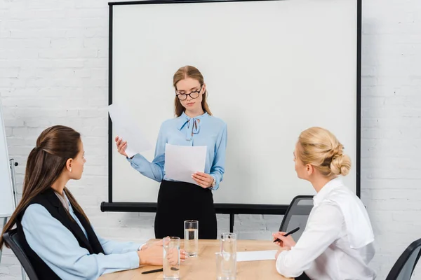 Mulheres de negócios jovens bonitas que têm a conversação com o chefe no escritório moderno — Fotografia de Stock