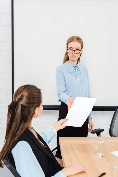 Young manageresses passing documents during conversation — Stock Photo