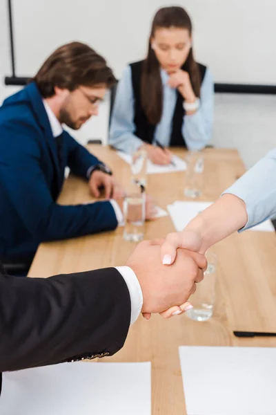Обрезанный снимок бизнесменов, пожимающих руки во время встречи в современном офисе — стоковое фото