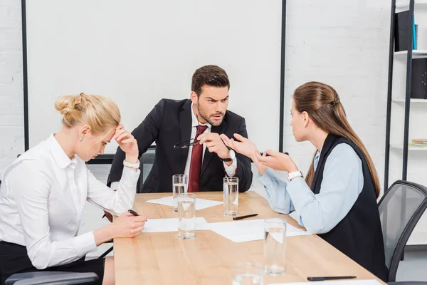 Jefe enojado hablando con sus colegas mujeres en la oficina moderna - foto de stock