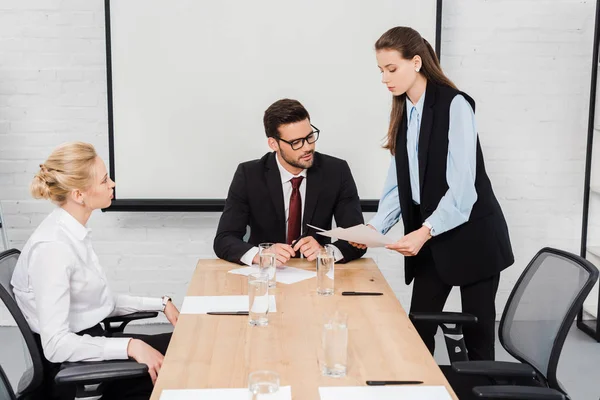 Jóvenes empresarias mostrando documentos a su jefe en la oficina moderna - foto de stock