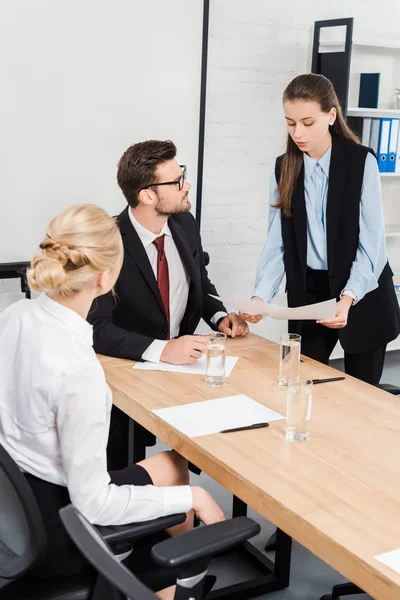 Attraktive junge Geschäftsfrauen zeigen ihrem Chef im modernen Büro Dokumente — Stockfoto