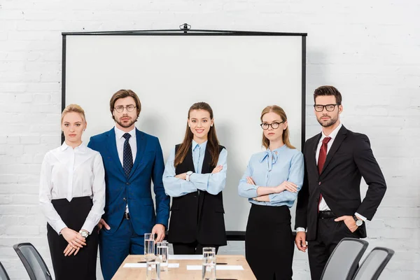 Team of business people standing at conference hall and looking at camera — Stock Photo